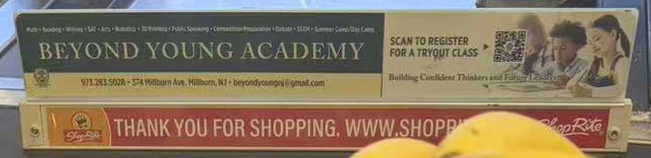 Close-up of the Beyond Young Academy sign on a ShopRite checkout lane divider: scan to register for a tryout class